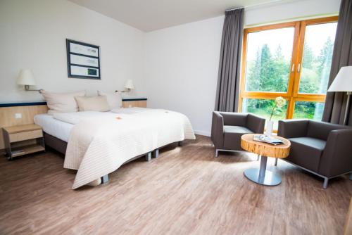a bedroom with a bed and a couch and a chair at Sporthotel Fuchsbachtal in Barsinghausen