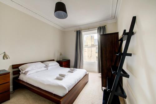een slaapkamer met een bed met witte lakens en een raam bij GuestReady - Amazing apt near The Meadows in Edinburgh