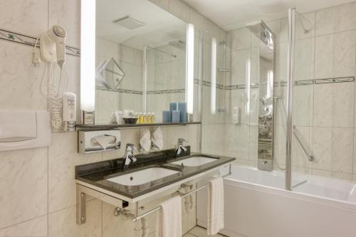 a bathroom with a sink and a shower and a tub at Hotel Simi in Zermatt