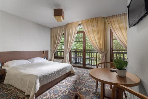 een slaapkamer met een bed en een tafel en ramen bij Osada Grzybowski Młyn in Grzybowski Młyn