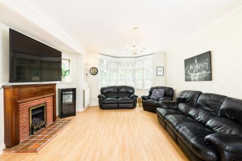 a living room with black leather furniture and a fireplace at Beautiful 6 bedroom house for 17 guests next to Edgbaston Stadium in Birmingham