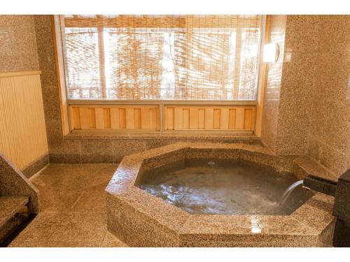 baño con bañera de piedra grande y ventana en Hotel Castle Inn Ise Meotoiwa, en Ise