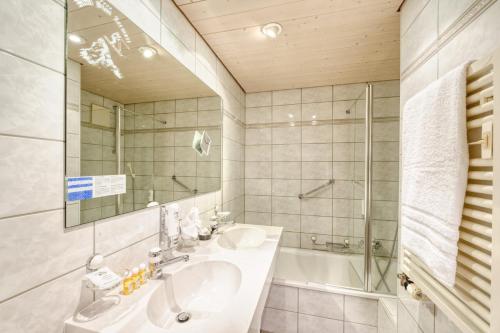 un bagno con un lavandino, una vasca e uno specchio di Hotel Simi a Zermatt