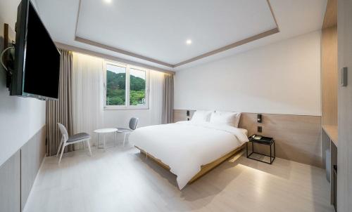 um quarto com uma cama, uma mesa e uma televisão em Geoje Mongdol Beach H Avenue Hotel em Geoje