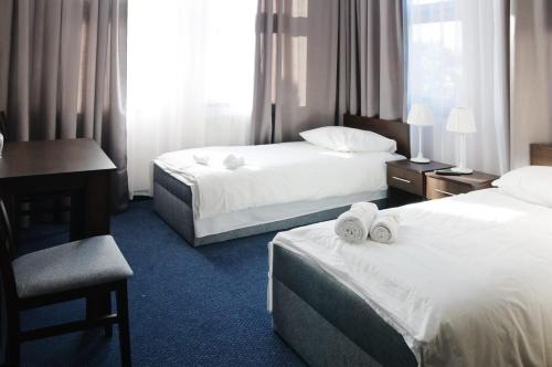 a hotel room with two beds and a desk at Baza Hotelowa Bobrowiecka 9 in Warsaw