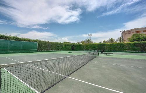 a tennis court with a net and a bench at Crowne Plaza Resort Salalah, an IHG Hotel in Salalah