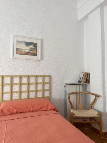 Apartamento Único en Plaza del Pilar في سرقسطة: غرفة نوم بسرير وكرسي وصورة