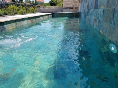 a swimming pool filled with blue water next to a wall at Vila Hercegovka in Trebinje