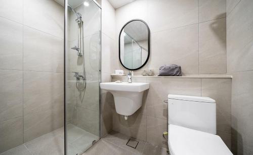 a bathroom with a toilet and a sink and a mirror at Geoje Mongdol Beach H Avenue Hotel in Geoje 