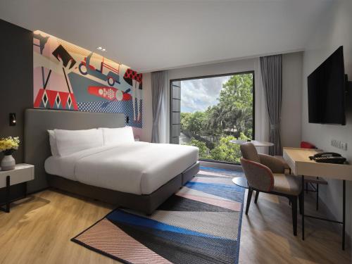 a hotel room with a bed and a desk and a window at Oakwood Studios Sukhumvit Bangkok in Bangkok