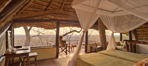 a bedroom with a bed and a balcony with a view at Elewana Elsa's Kopje in Meru