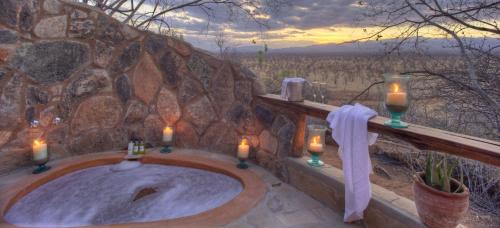 a bathroom with a bath tub with candles and lights at Elewana Elsa's Kopje in Meru