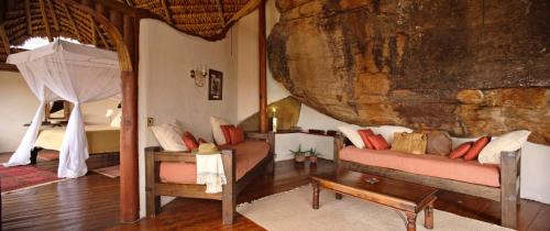a room with a bed and a couch and a bedroom at Elewana Elsa's Kopje in Meru
