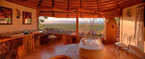 a bathroom with a tub and two sinks and a window at Elewana Elsa's Kopje in Meru