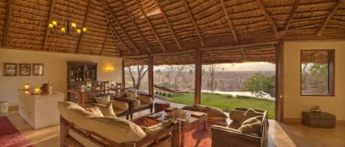 a living room with couches and a large window at Elewana Elsa's Kopje in Meru