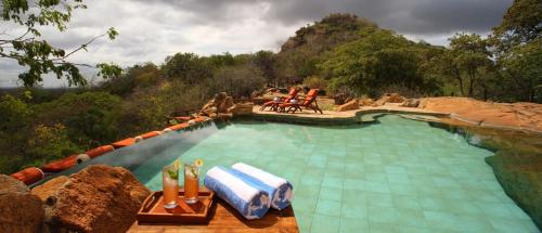 a large swimming pool with chairs and a mountain at Elewana Elsa's Kopje in Meru