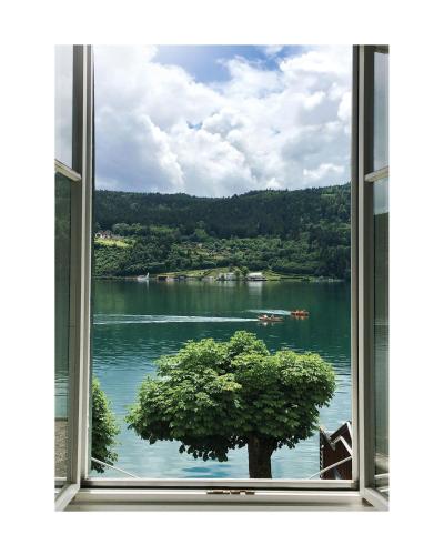 a window with a view of a tree in the water at Villa Streintz in Millstatt
