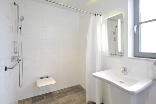 y baño blanco con lavabo y ducha. en ibis De Panne en De Panne