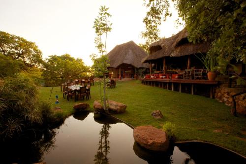 a resort with a pond and tables and chairs at Elewana Elsa's Kopje in Meru