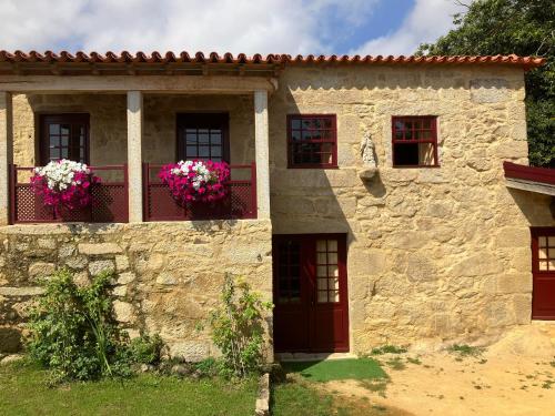 a stone house with flowers on a balcony at Casa do Cruzeiro do Outeiro -comfort and tradition in Ponte de Lima