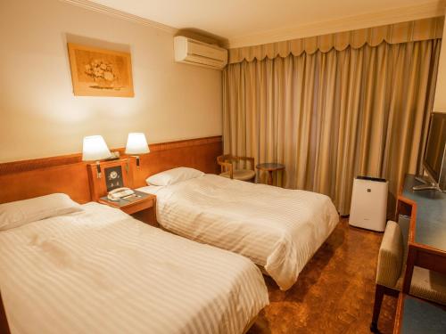 鈴鹿市にあるHotel Castle Inn Suzuka Chuoのベッド2台とテレビが備わるホテルルームです。