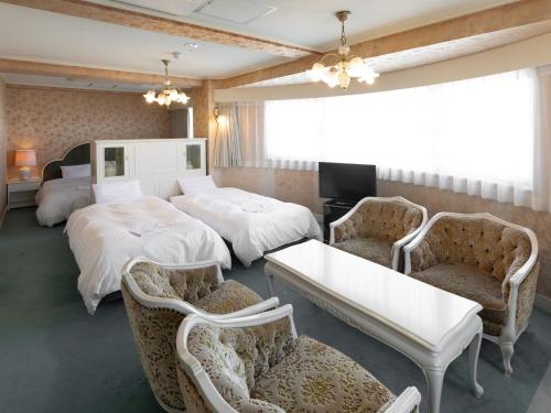 a hotel room with two beds and two chairs at Hotel Castle Inn Yokkaichi in Yokkaichi