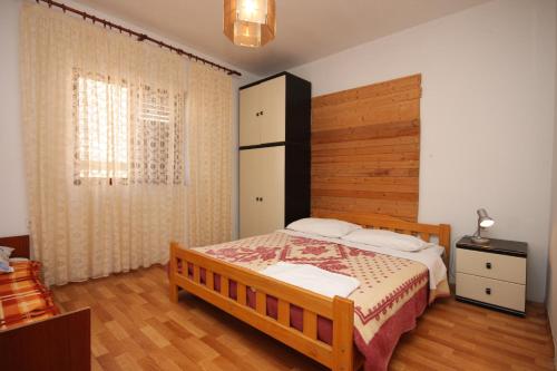 a bedroom with a bed with a wooden headboard at Apartments by the sea Metajna, Pag - 6352 in Metajna