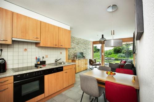 eine Küche mit Holzschränken und einem Tisch mit roten Stühlen in der Unterkunft Panoram'Alp in Savièse