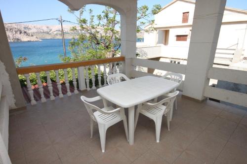 a white table and chairs on a balcony with the ocean at Apartments by the sea Metajna, Pag - 6352 in Metajna