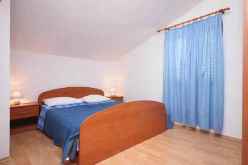 a bedroom with a bed and a blue curtain at Apartments by the sea Petrcane, Zadar - 6269 in Petrcane