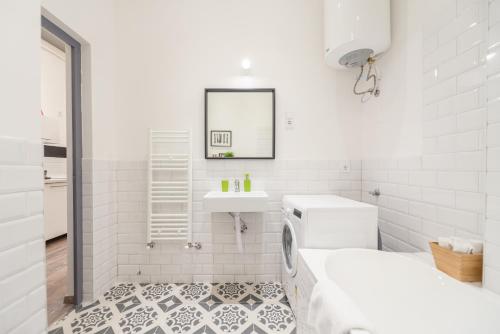 ein weißes Badezimmer mit einem Waschbecken und einer Waschmaschine in der Unterkunft Venus Apartments - Almassy Park in Budapest