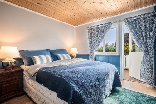 a bedroom with a blue bed and a window at Klara in Sandefjord