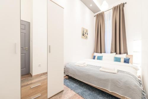 ein Schlafzimmer mit einem Bett mit blauen Kissen und einem Fenster in der Unterkunft Venus Apartments - Almassy Park in Budapest