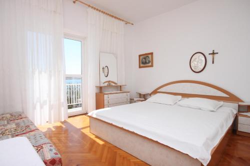 a white bedroom with a large bed and a window at Rooms by the sea Kustici, Pag - 6288 in Kustići
