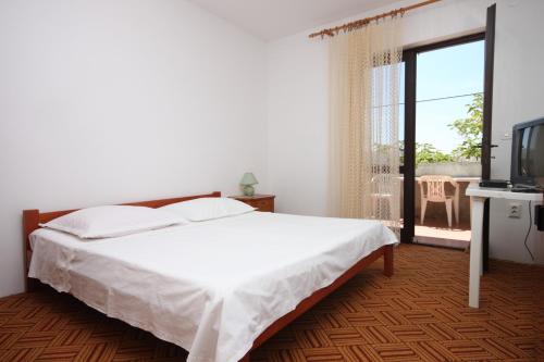 ズボヴィチにあるApartments with a parking space Zubovici, Pag - 6409のベッドとテレビとバルコニーのある寝室