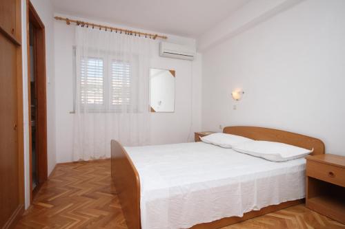 a white bedroom with a bed and a window at Apartments with a parking space Kustici, Pag - 6287 in Kustići