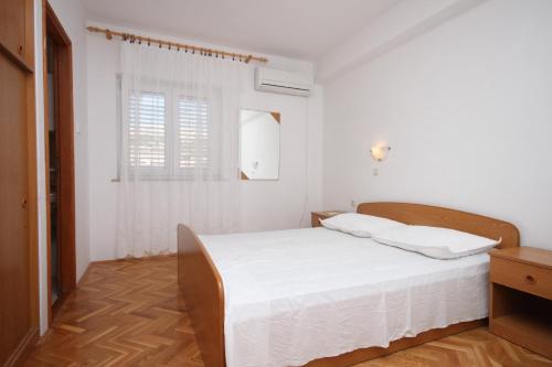 a white bedroom with a bed and a window at Apartments with parking space Kustici, Pag - 6287 in Kustići