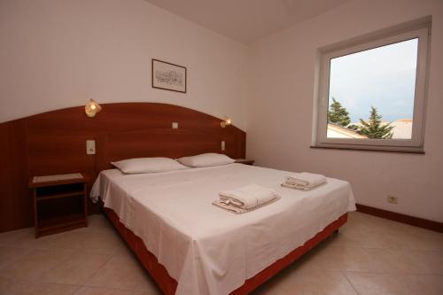 a bedroom with a large bed with white sheets and a window at Apartments with a parking space Novalja, Pag - 6398 in Novalja