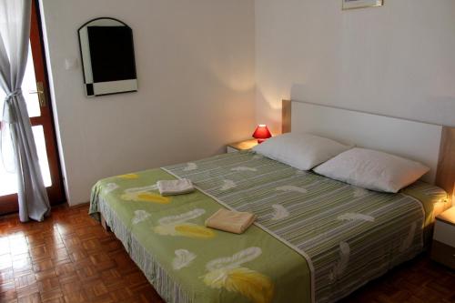 een slaapkamer met een bed met een groene en gele deken bij Apartments by the sea Sukosan, Zadar - 6402 in Sukošan