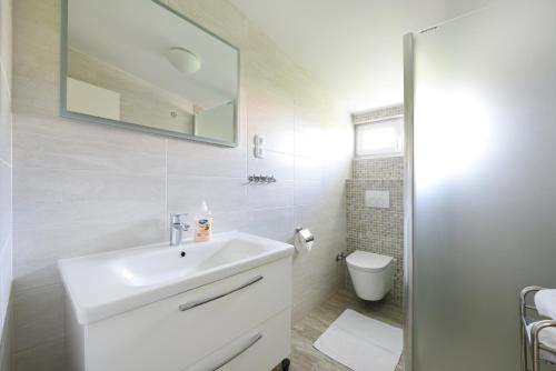 a white bathroom with a sink and a toilet at Apartments with a parking space Vodice - 6271 in Vodice