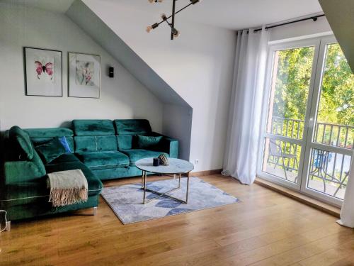 a living room with a green couch and a table at Zielony apartament z widokiem na jezioro in Złotów