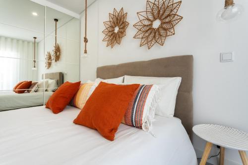 a bedroom with a bed with orange pillows and a mirror at Privilege Deluxe Apartment Casa Mãe, Faro in Faro