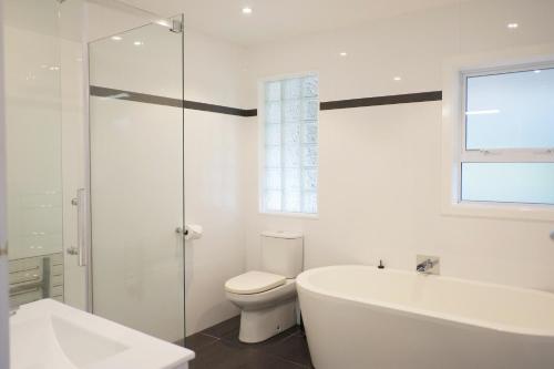 a white bathroom with a tub and a toilet at Tranquil mountain peak in Rotorua