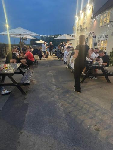 a group of people sitting at picnic tables on a street at Yarm Cottages Sleeping 6 Next to Fox Covert Pub in Kirk Leavington