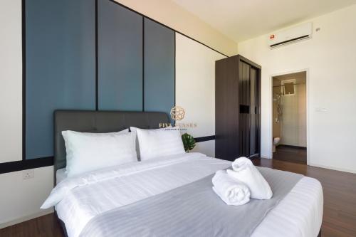 a bedroom with a large white bed with towels on it at UNA Serviced Apartment, Sunway Velocity Kuala Lumpur in Kuala Lumpur