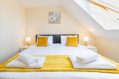 - une chambre avec un grand lit blanc et des oreillers jaunes dans l'établissement Velvet 1-bedroom penthouse, Clockhouse, Hoddesdon, à Hoddesdon