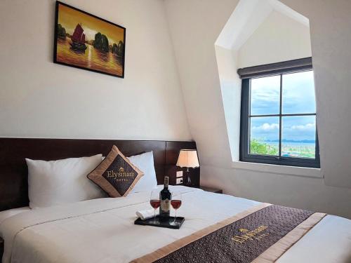 a bedroom with a bed with two glasses of wine at Elysinam Boutique Hotel Ha Long in Ha Long