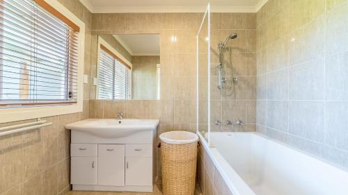 een badkamer met een bad, een wastafel en een douche bij Loch Retreat 550M To Town in Inverloch