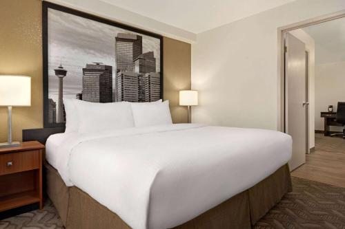 uma grande cama branca num quarto de hotel em Super 8 by Wyndham Calgary Shawnessy Area em Calgary