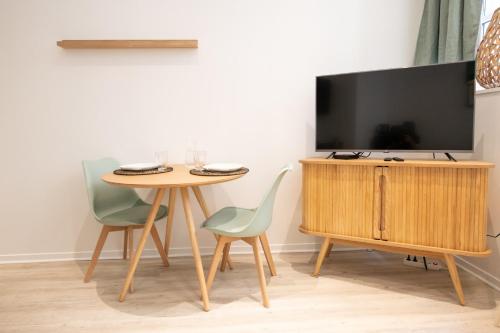 ein Esszimmer mit einem Tisch und einem TV in der Unterkunft L'Opéra 2 - RDC - Joli studio Hôtel de Ville in Lyon